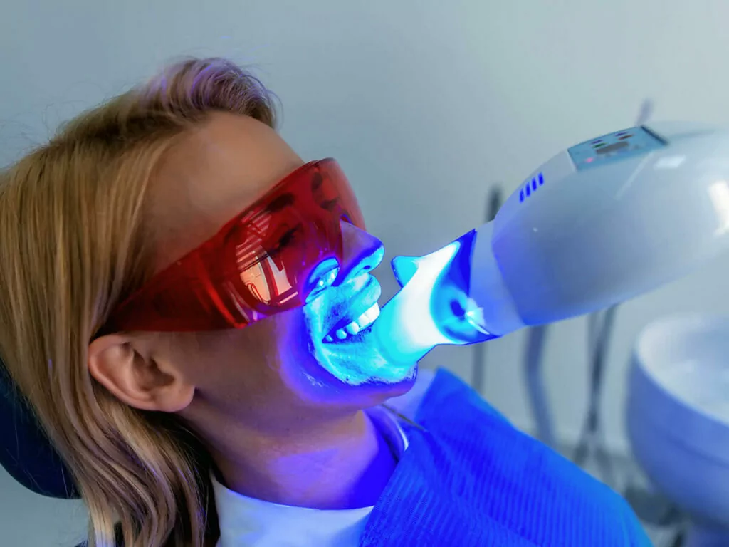 Patient getting her teeth whitened with UV light